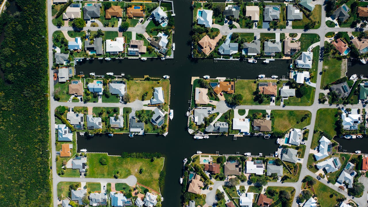Drone shot of suburban canal-side homes arranged neatly with clear water channels.
